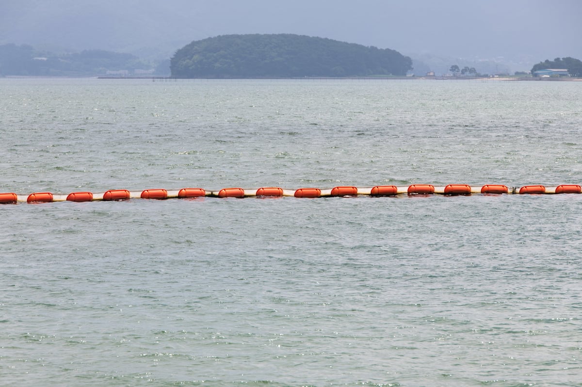Line of orange floating containment buoys forming a barrier on the water